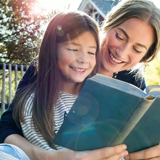 Mutter und Tochter lesen Buch in Garten