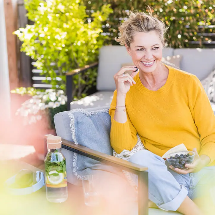 Frau isst Heidelbeeren auf Terrasse