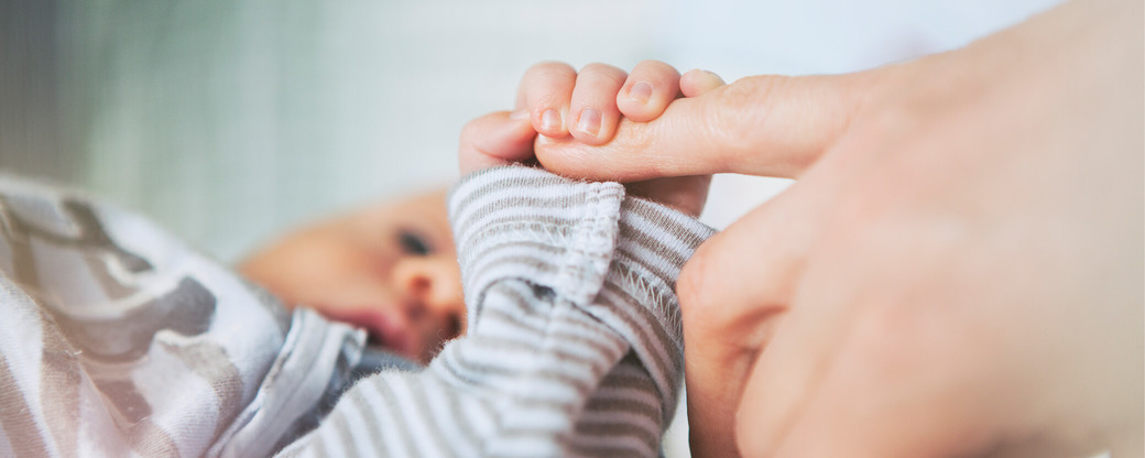 Baby hält Finger der Mutter