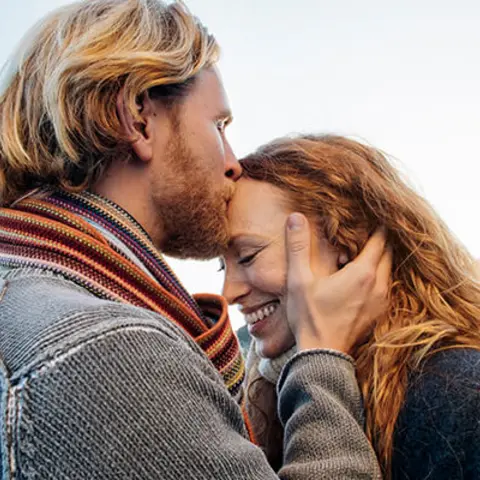 Mann küsst Frau auf Stirn