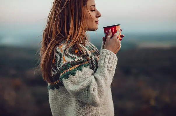 Frau trinkt Heißgetränk in der Natur