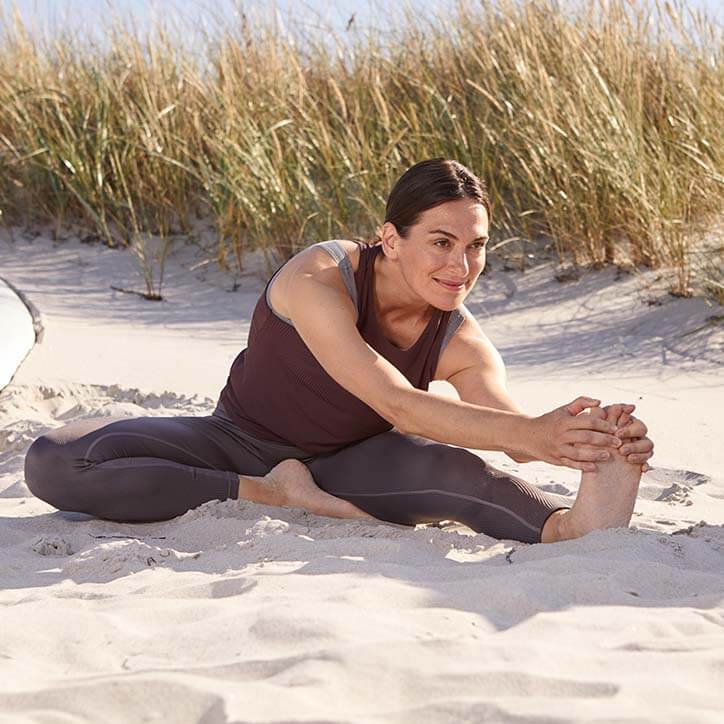 Frau dehnt sich am Strand