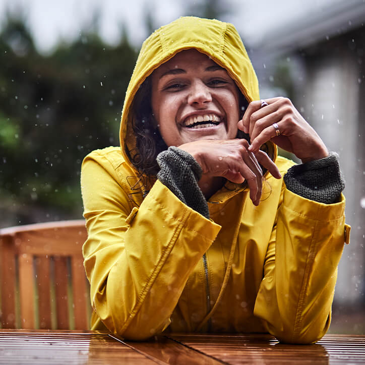 Frau im Regenmantel stärkt draußen ihr Immunsystem.