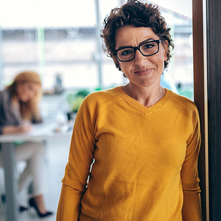 Frau mit Brille lehnt an Wand