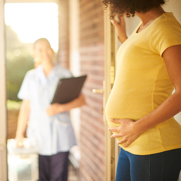 Schwangere öffnet Tür für Hebamme